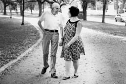 senior gentleman and adult woman walking in a park holding hands