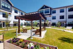 sunny courtyard with pergola and raised flower beds at Quartet Senior Living