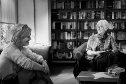 A mature adult woman in an welcoming naturally-lit office talking with a fellow professional business woman